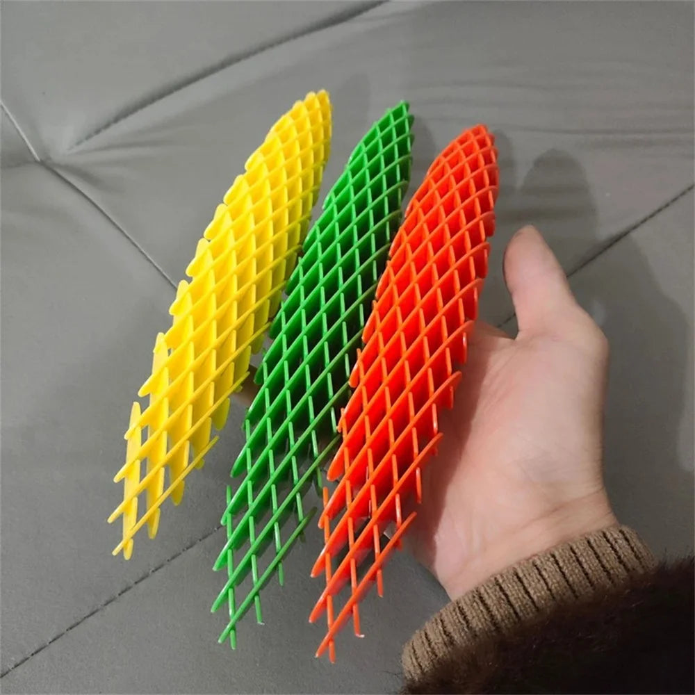 Three colorful plastic shims (yellow, green, orange) held by a hand on a gray surface.