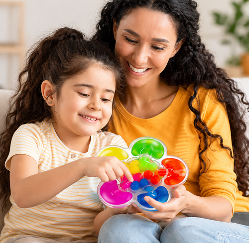 Child playing with colourful sensory colour sorting toy with adult support to improve focus and learning
